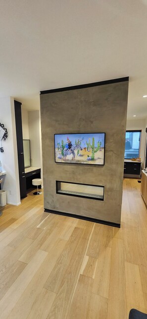 Ein modernes Wohnzimmer mit Wand-Fernseher, Holzboden und minimalistischem Design.