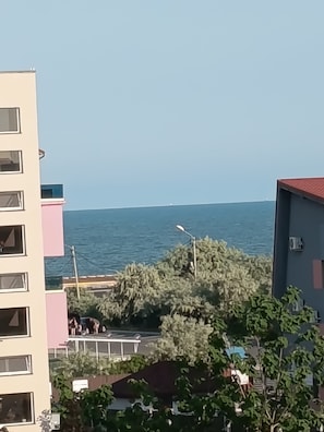 Un bâtiment situé sur la côte, doté de nombreux balcons, offrant une vue sur la mer et agrémenté de quelques espaces verts.