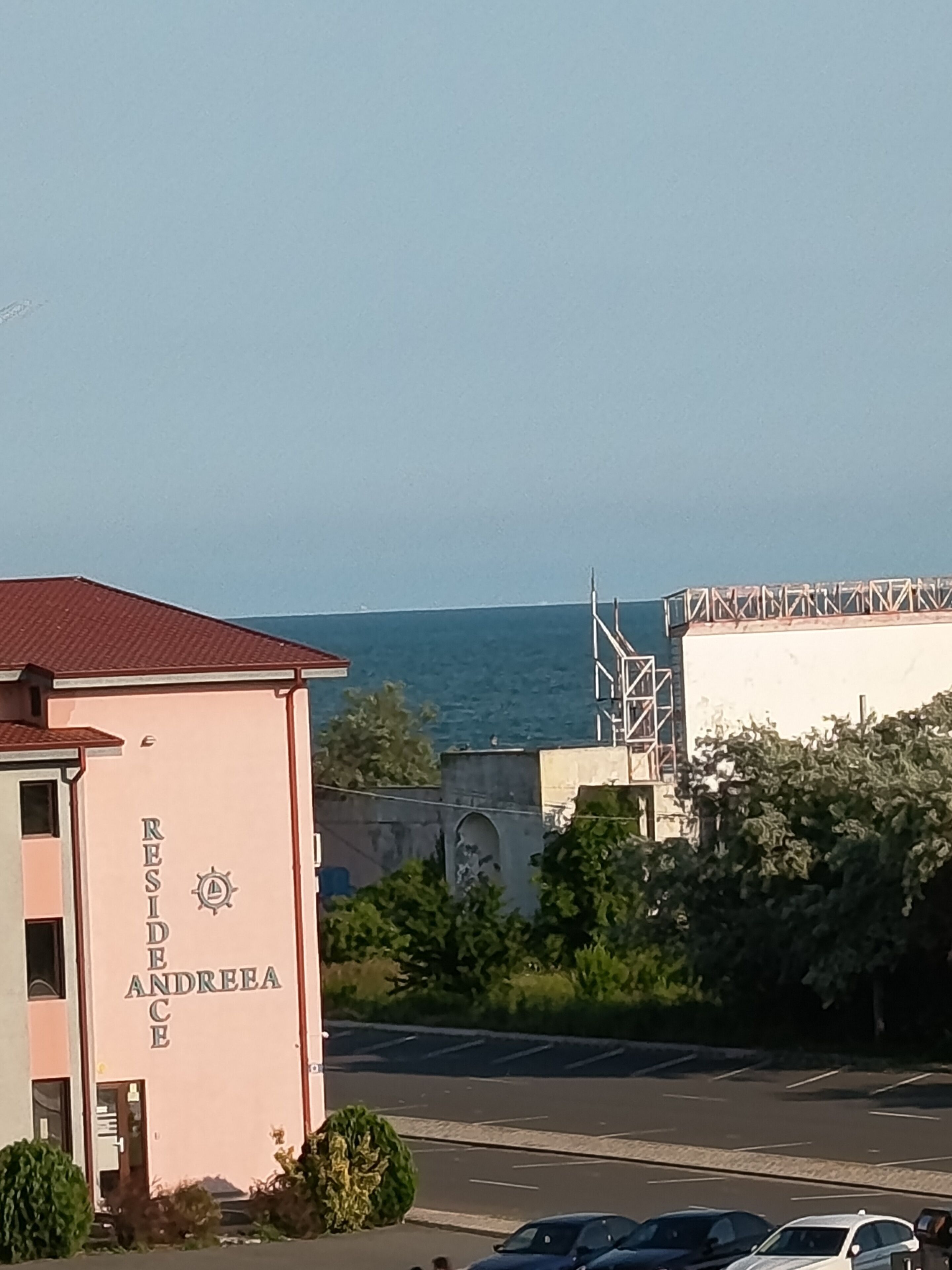 A building with a sign reading 'RESIDENCE ANDREA' and a view of the sea in the background.