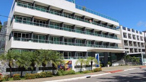 A multi-story building with balconies, a central entrance, and a landscaped area with palm trees. - Blue Sunset Cabo Branco | Beachfront Apartment (João Pessoa)