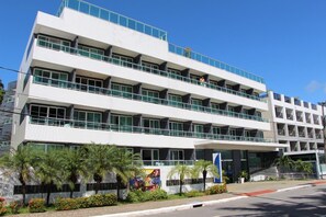 A multi-story building with balconies, a central entrance, and a landscaped area with palm trees. - Blue Sunset Cabo Branco | Beachfront Apartment (João Pessoa)