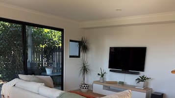A modern living room with a sofa, a TV, and a potted plant.