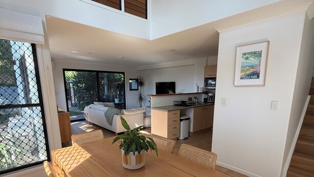 A modern kitchen with a dining area, a large window, and a staircase. - Beach Stay | Walk to the Surf, Café & Shops (Coolum Beach)