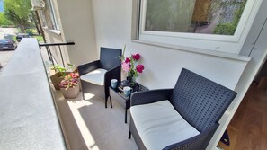 En balkon med fletmøbler, en potteplante og en vase med blomster.