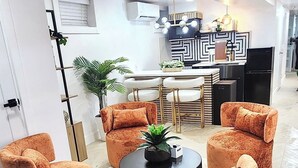 A modern living room with a round coffee table, four orange armchairs, a dining table with chairs, and a kitchen area with a geometric backsplash. - Luxe 3BR with 3 Private Bathrooms Near Airport and 30 mins to NYC (Newark)