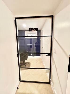 A door with a sign reading 'Le Chatou Office' leading to a room with a chair and a tiled floor. - Luxe 3BR w/Private Bath in Every BR Near Airport (Newark)