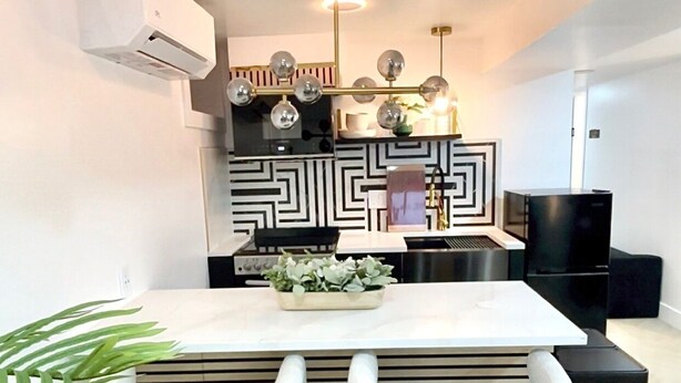A modern kitchen with a central island, pendant lighting, and a black and white patterned backsplash. - Luxe 3BR with 3 Private Bathrooms Near Airport and 30 mins to NYC (Newark)