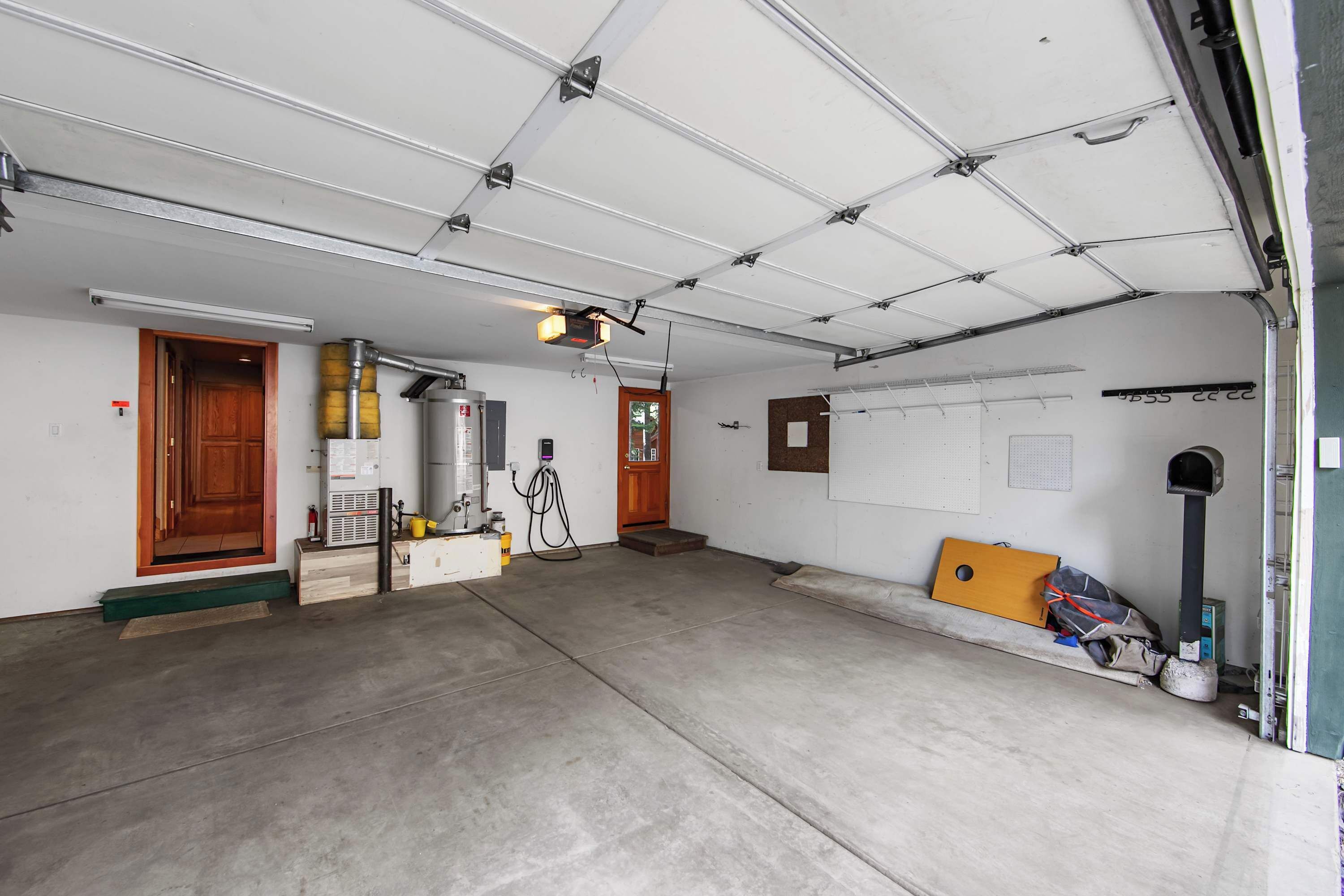 A garage with a concrete floor, a wooden door, a yellow toolbox, and a black mailbox.