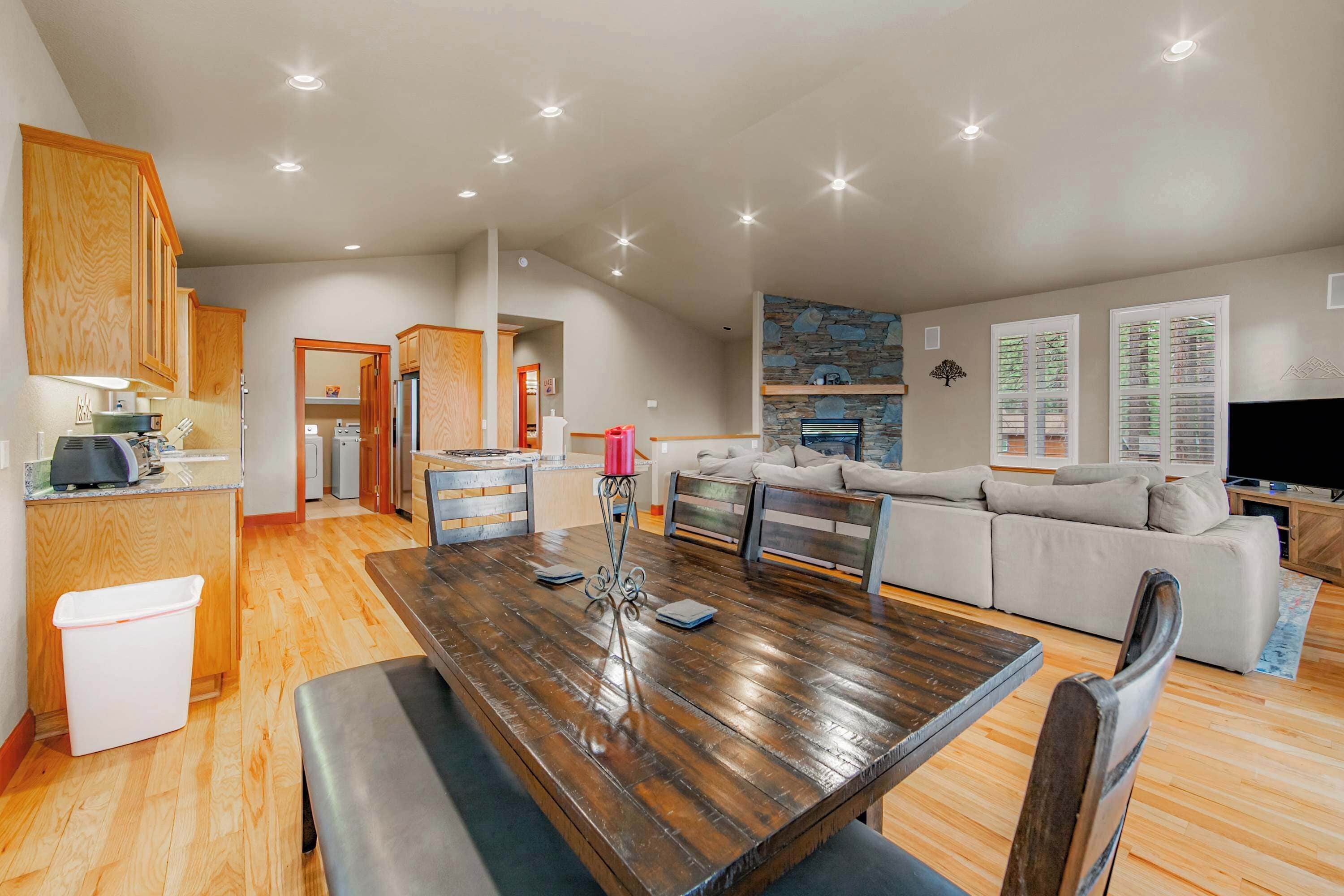 Amplia sala de estar con una mesa de comedor de madera, un sofá y una cocina al fondo.