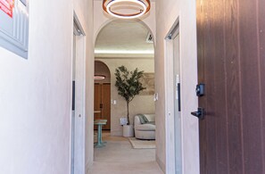 Ein Korridor mit gewölbter Decke, einer Holztür, einem kleinen Tisch, einer Topfpflanze und einem Sofa.