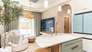 Eine moderne Küche mit einer großen Kochinsel, einem eingebauten Backofen und einem flachbildfernseher an der Wand.
