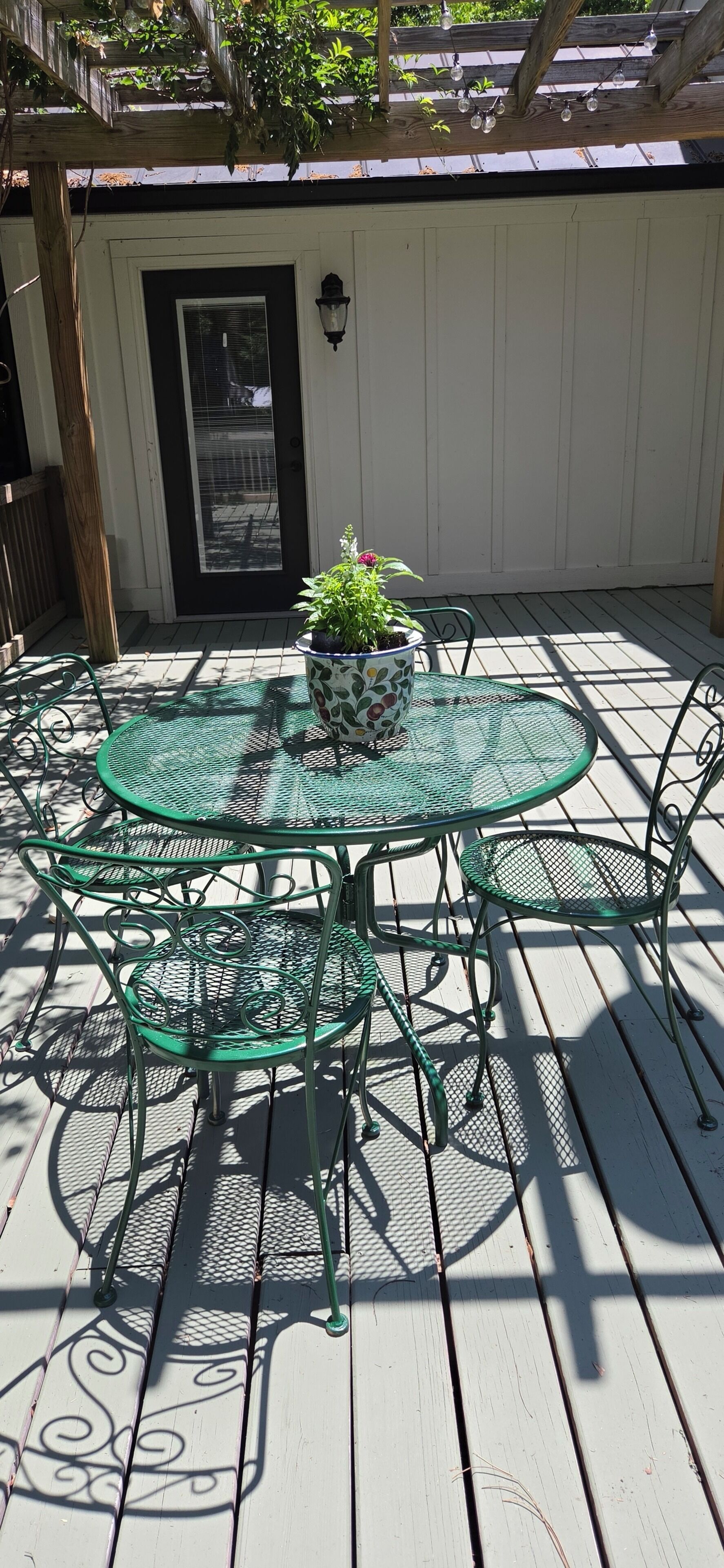 A patio with a round table and chairs, a potted plant, and a door with a window.