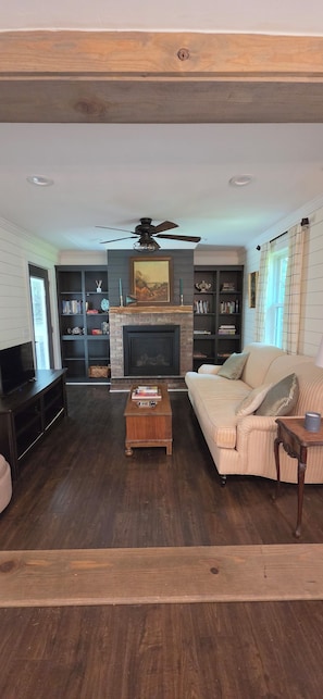 A living room with a fireplace, bookshelves, a sofa, and a television.