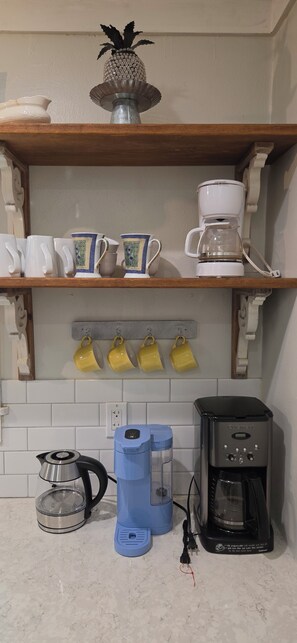 Keittiössä on kahvinkeitin, vedenkeitin ja espressokone työtasolla.