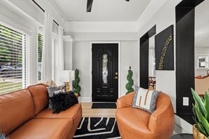 Ein modernes Wohnzimmer mit einer schwarzen Tür, weißen Wänden und einem schwarz-weißen Teppich.