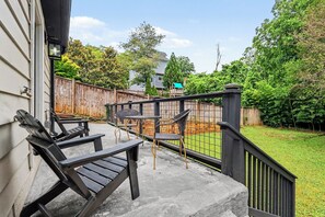 Eine Terrasse mit Gartenmöbeln, einem Holzzaun und einem Rasen.
