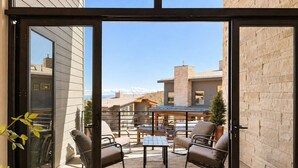 Patio esterno moderno con tavolo e sedie, vista sugli edifici circostanti e cielo sereno.