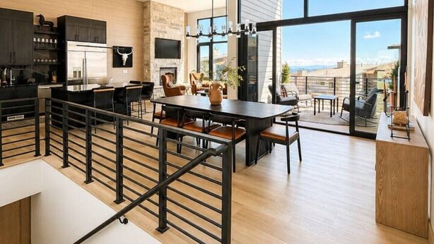 Una cucina moderna con una grande isola, un'area pranzo con vista e una scala che conduce a un piano superiore.