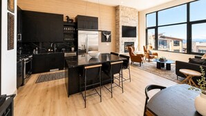 Una cucina moderna con isola centrale, mobili neri e un'ampia finestra con vista sulla città.