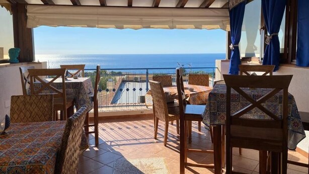 A terrace with wooden furniture, a view of the sea, and a patterned tablecloth. - Hellas  (Macari)