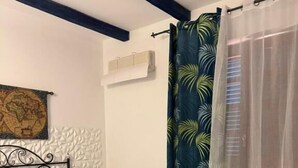 A bedroom with a bed, a chair, a map on the wall, and a curtain with a leaf pattern. - Hellas  (Macari)