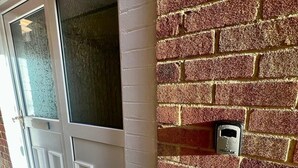 A house exterior with a white door, a window with frosted glass, and a brick wall with a mailbox.