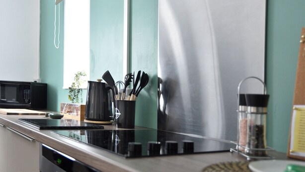 A kitchen with a microwave, stove, and utensils.