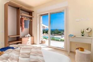 A bedroom with a bed, a wardrobe, a desk with a mirror, and a view of a pool and landscape. - High-end pool villa on 2 levels with sea view (Torre Pali)