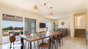 A spacious dining area with a long table, multiple chairs, and pendant lighting. - High-end pool villa on 2 levels with sea view (Torre Pali)