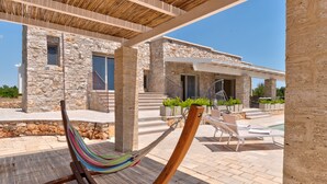 A hammock under a pergola, stone building, outdoor seating, and a pool area. - High-end pool villa on 2 levels with sea view (Torre Pali)