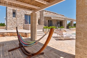 A hammock under a pergola, stone building, outdoor seating, and a pool area. - High-end pool villa on 2 levels with sea view (Torre Pali)