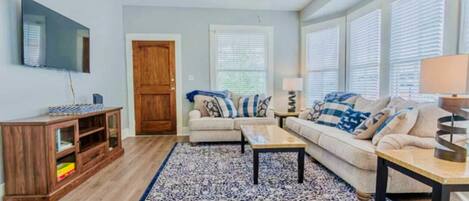 A living room with a wooden cabinet, a sofa set, a coffee table, a TV, and a ceiling fan.