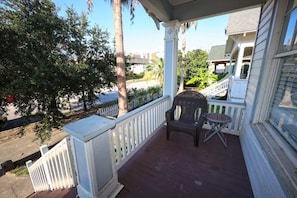 A porch with a white railing, a chair, and a small table. - Uptown Cottage Near Downtown (Galveston)