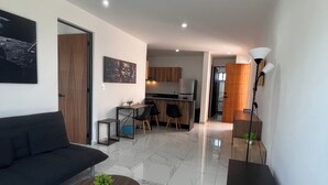 Een moderne woonkamer met een bank, een salontafel en een eethoek met stoelen en een tafel.