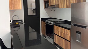 Een moderne keuken met een zwart aanrecht, houten kastjes, een roestvrijstalen koelkast en een inbouwoven.
