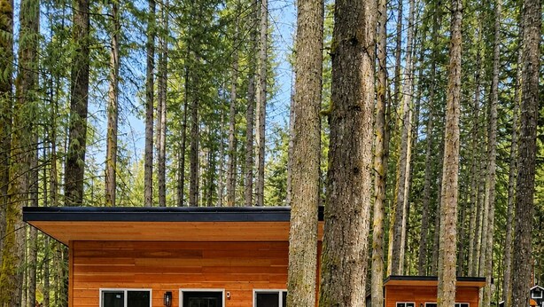 Une cabane avec une façade en bois, deux portes et une allée gravillonnée.