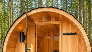 Un sauna en bois doté d’un toit incurvé, d’un banc, d’un appareil de chauffage et d’un panneau de commande.