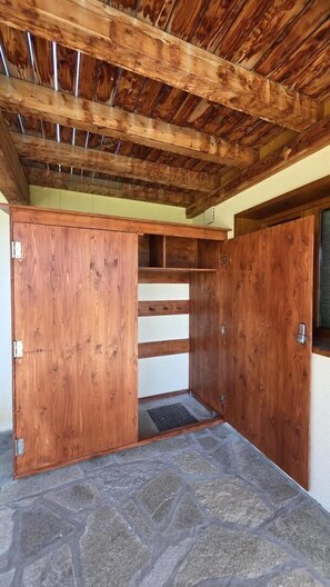 Ein Zimmer mit Steinboden, Holzbalken an der Decke und einem eingebauten Holzschrank mit Schiebetür.