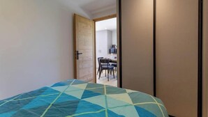 Een slaapkamer met een bed, een houten deur en uitzicht op een eetruimte.