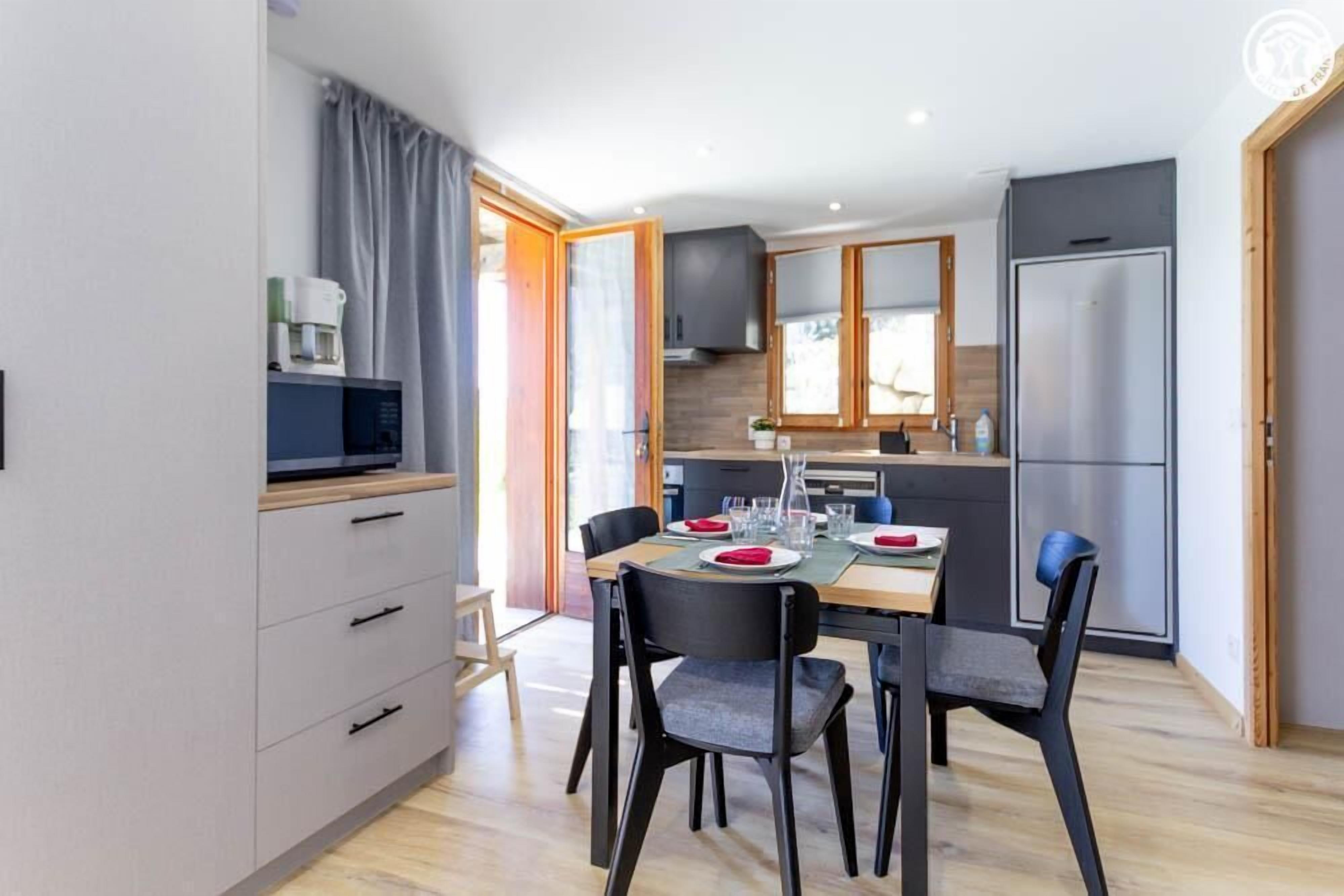 A modern kitchen with a dining table set for four, a microwave, and a refrigerator.