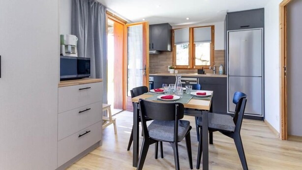 Een moderne keuken met een eettafel voor vier personen, een magnetron en een koelkast.