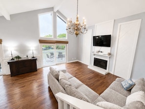Ein Wohnzimmer mit Sofa, einem Chandelier, einem Kamin und einem an der Wand befestigten Fernseher.