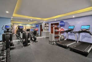 Uma academia com esteiras, máquinas de peso e bolas de exercício.