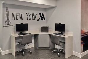 A modern office space with two desks, two monitors, and a 'NEW YORK' wall decoration.