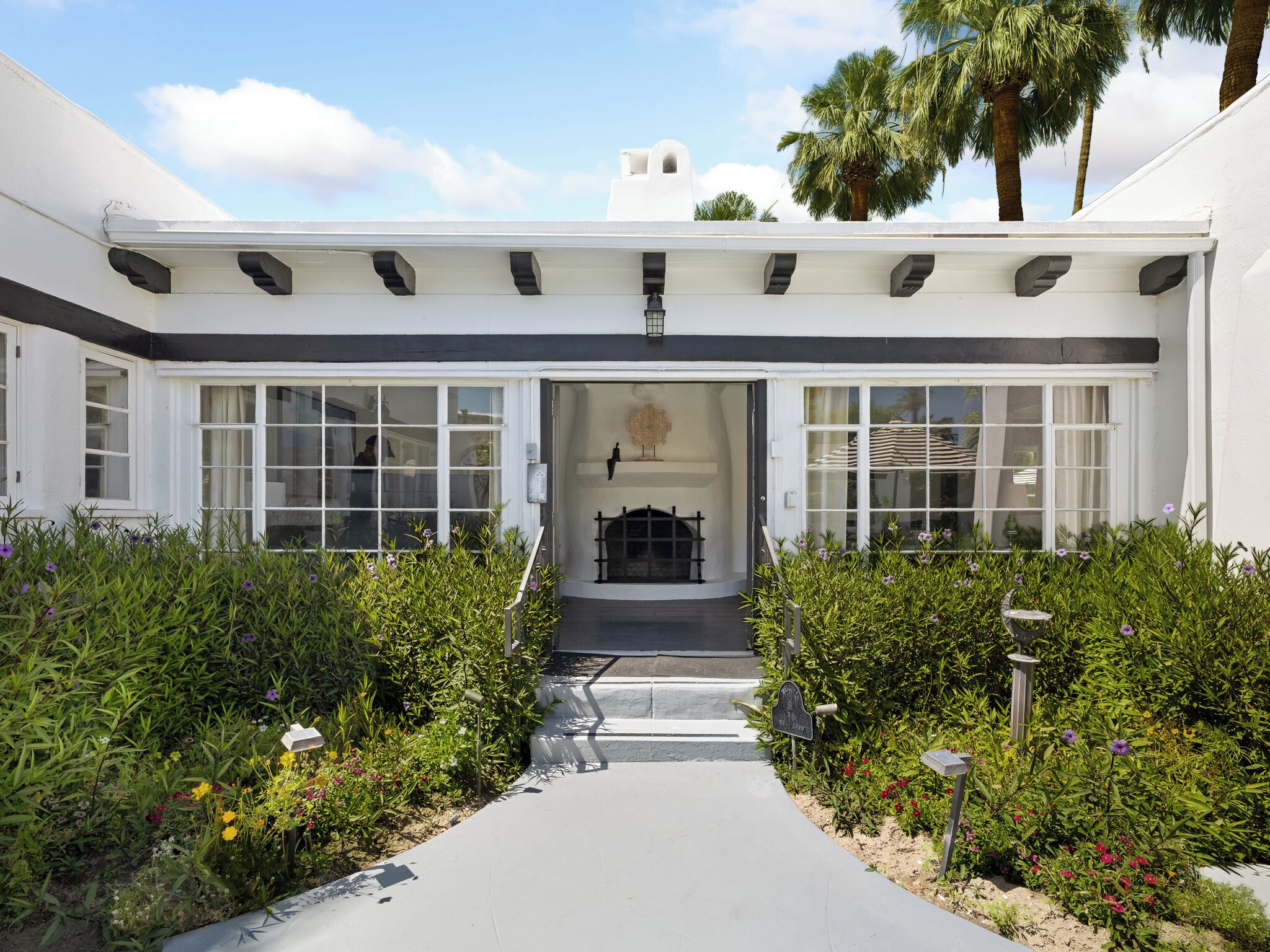 A building with a white facade, large windows, and a central entrance with steps leading to a covered area.