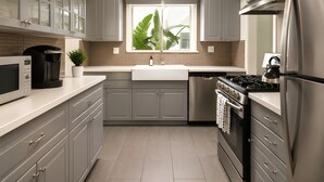 A modern kitchen with grey cabinets, a stainless steel refrigerator, a built-in oven, and a microwave. - Gloria Palm Springs (Palm Springs)