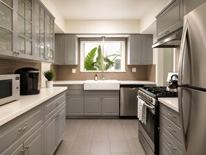 Una cocina moderna con armarios grises, un refrigerador de acero inoxidable, un horno empotrado y un microondas.