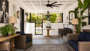 A room with wicker furniture, a ceiling fan, a potted plant, and a view through a glass door. - Gloria Palm Springs (Palm Springs)