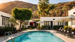 A swimming pool with lounge chairs and umbrellas, surrounded by greenery and a mountain backdrop. - Gloria Palm Springs (Palm Springs)