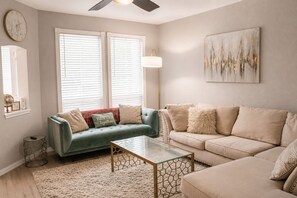 A living room with two sofas, a coffee table, a floor lamp, and a painting on the wall. - Plano Luxury Retreat · Hot Tub · Theater · Game Room Dallas/Frisco Sleeps 8 (Plano)